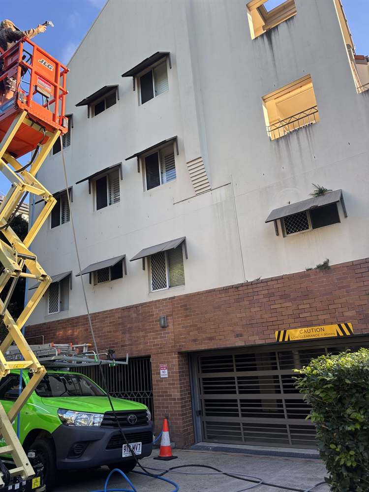 The Dript team cleaning a commercial building from a scissor lift in Brisbane