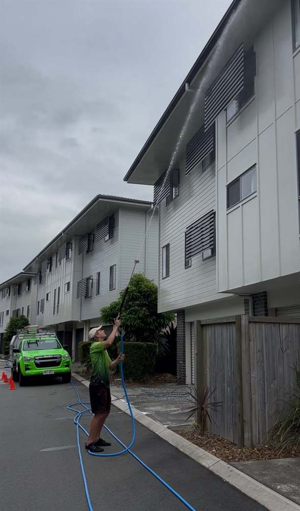 Dript team member soft washing a multi-storey building in Brisbane
